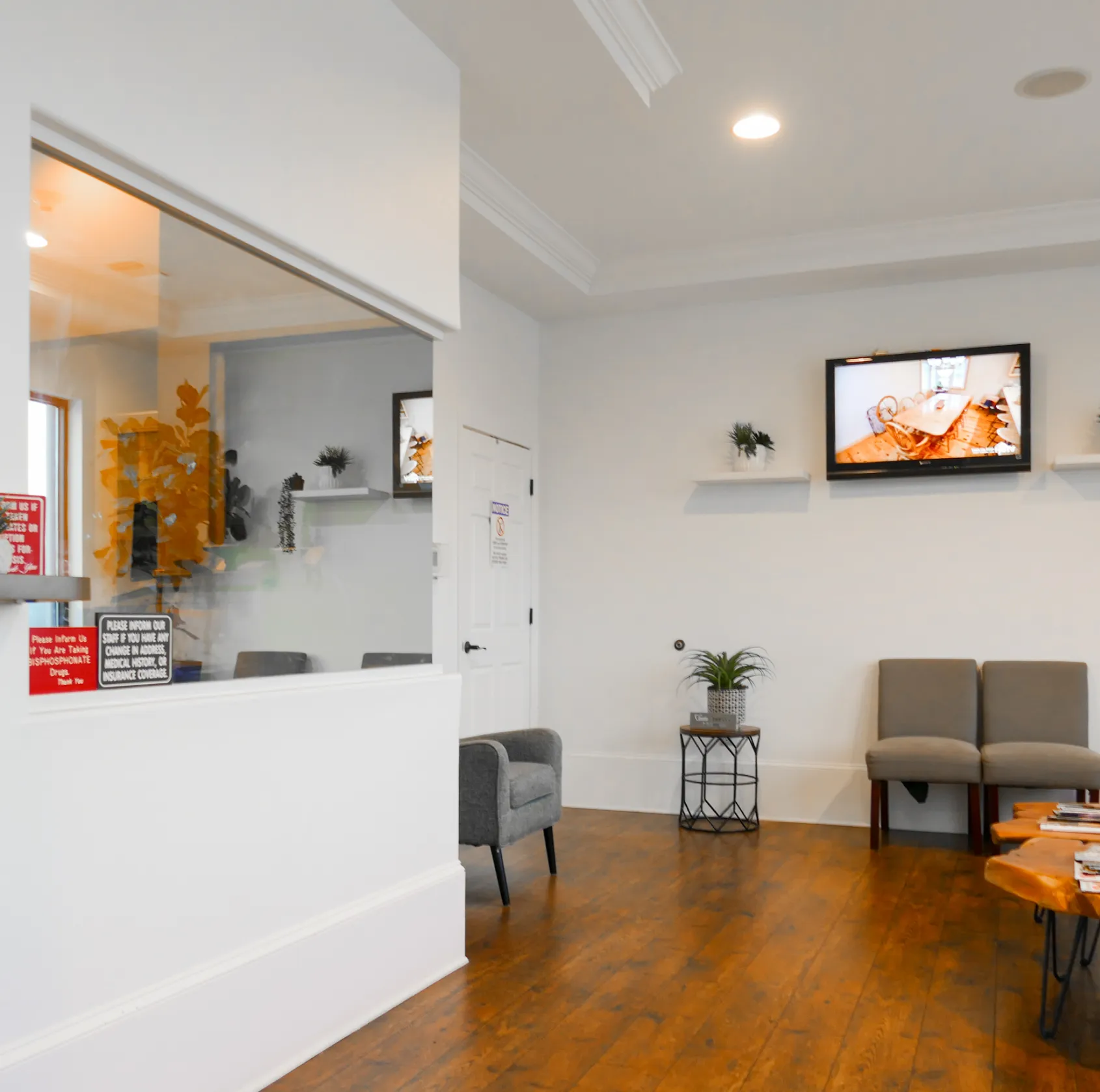 Waiting room with chairs, wall-mounted TV, and small table with magazines.
