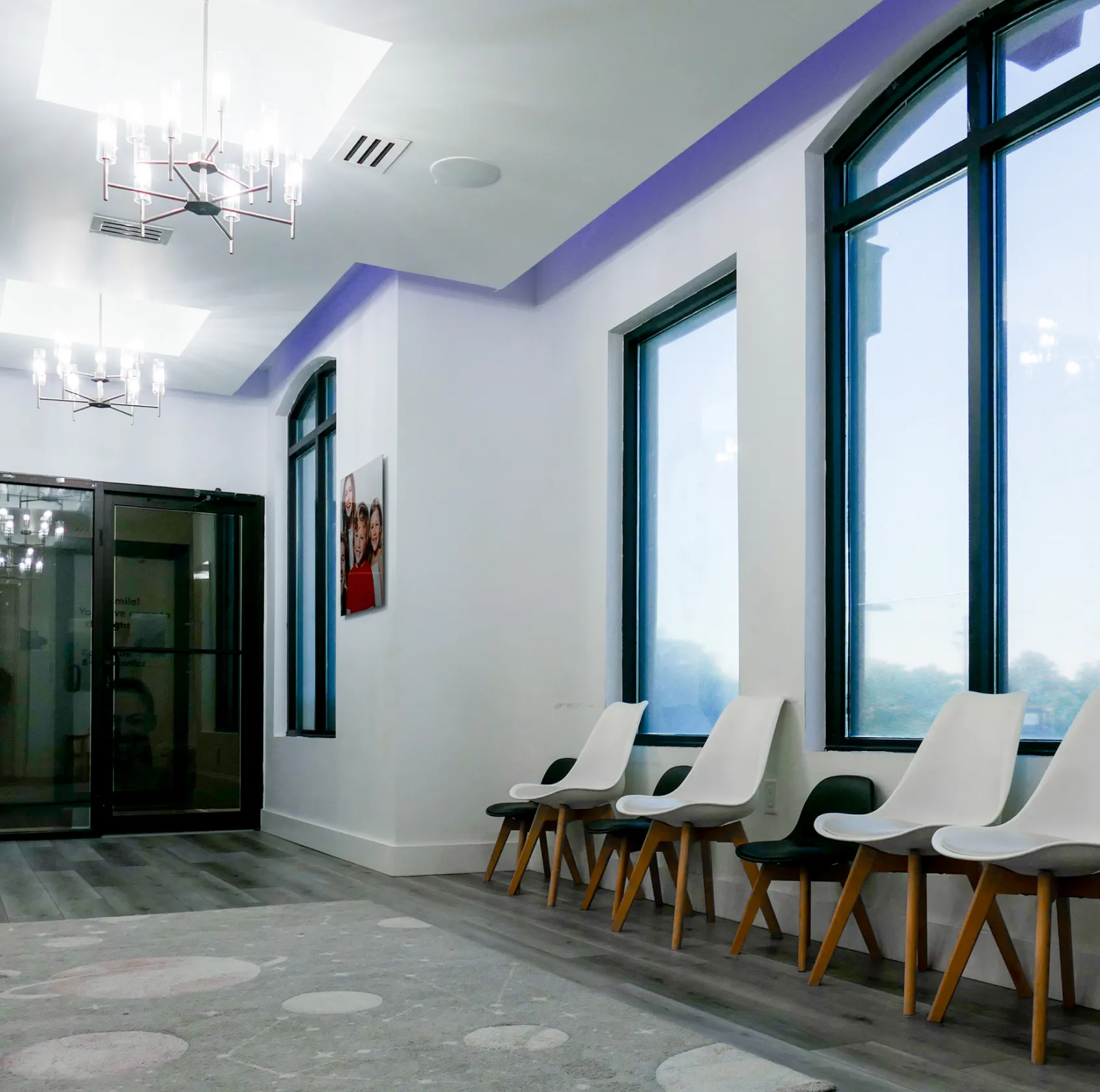 Dental office room with an empty dentist chair, equipment, and a monitor on the wall.