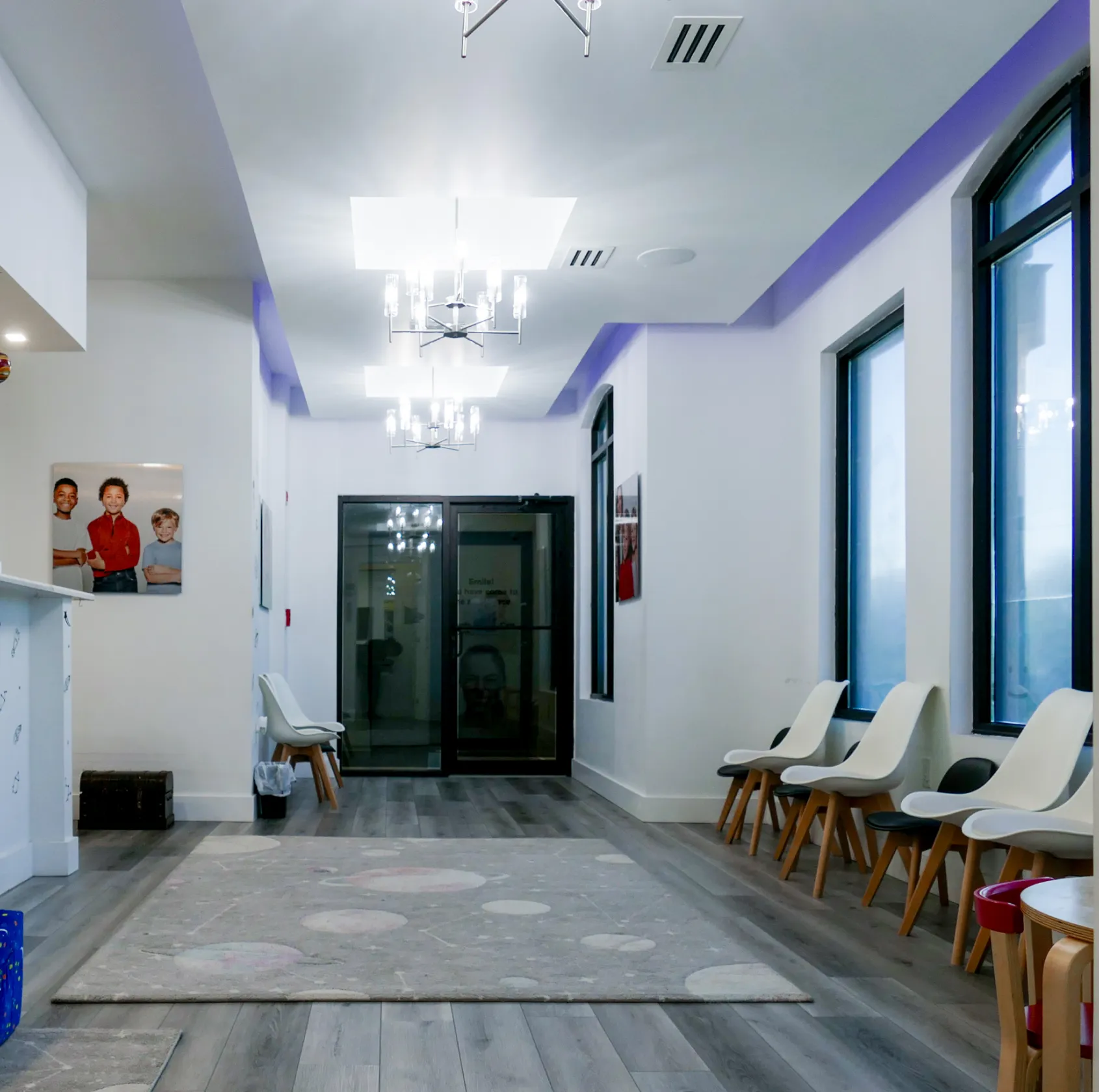 A waiting area with chairs along the walls and children's portraits on the walls.