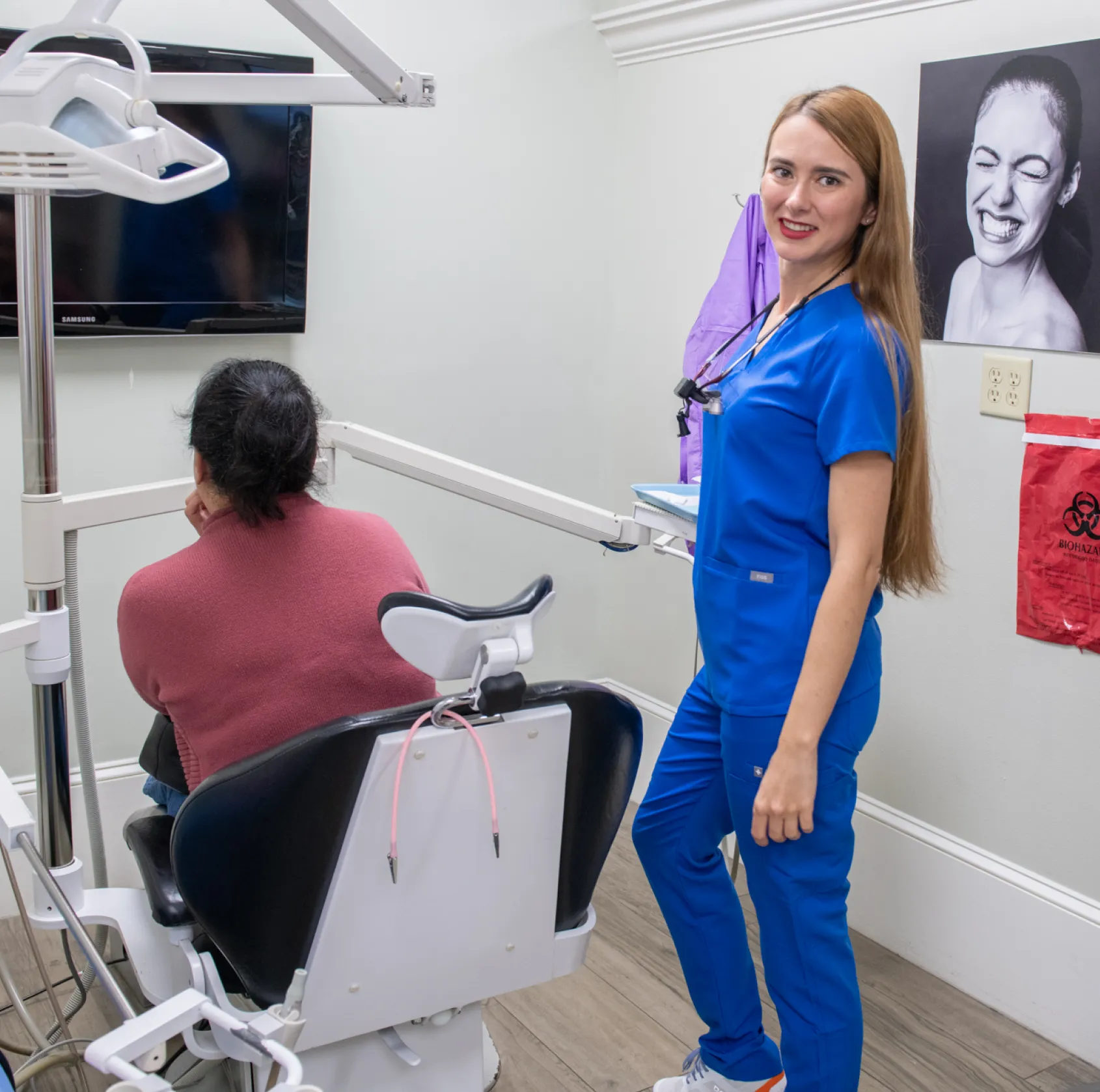 A man in a blue suit smiles, standing against a plain background.