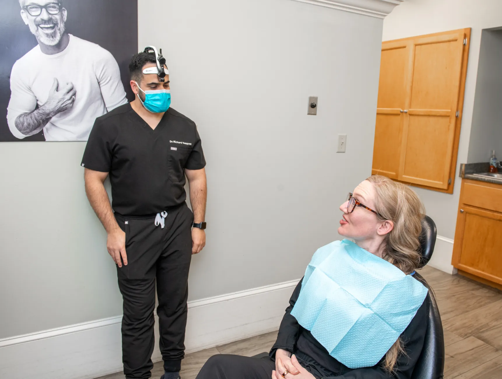 Four women, smiling and standing in a casual group, wearing black tops in a workplace setting.