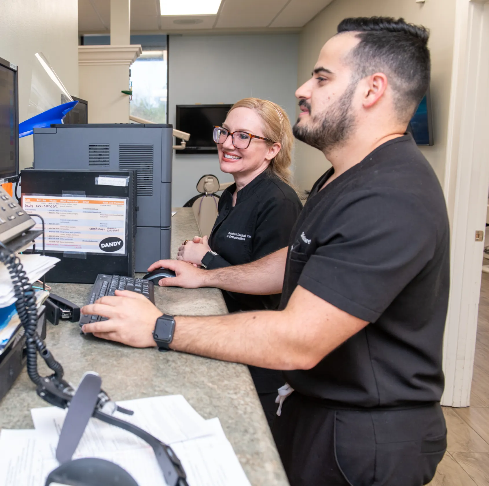 A smiling woman holds a plush dog toy in an office setting.