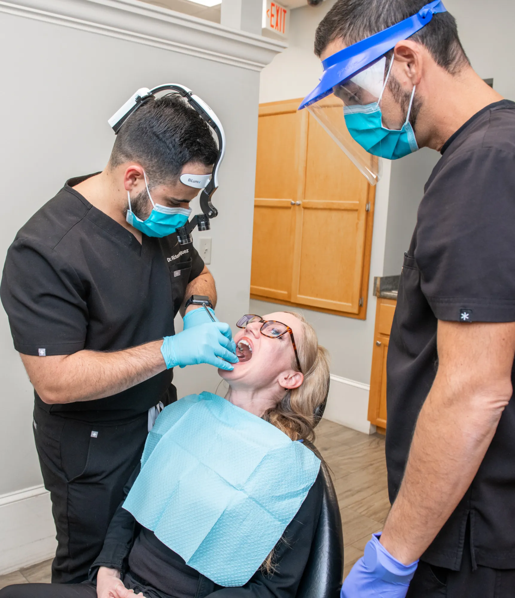 Seven people smiling and posing together inside a room with children's artwork on the wall.
