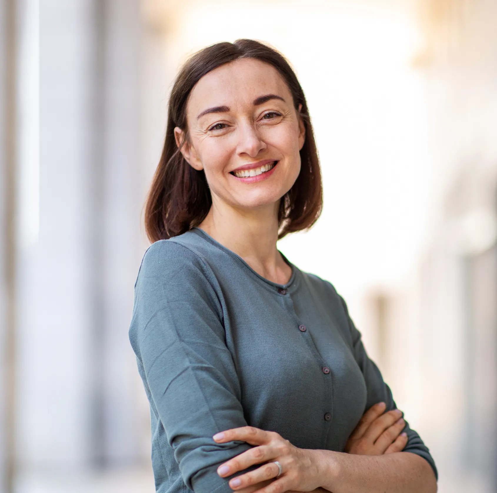A dentist in blue scrubs stands beside a patient seated in a dental chair.