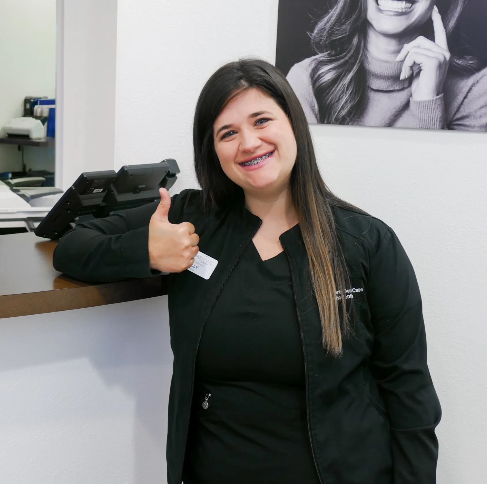 Person sitting at a workbench in a workshop, smiling and looking at the camera.