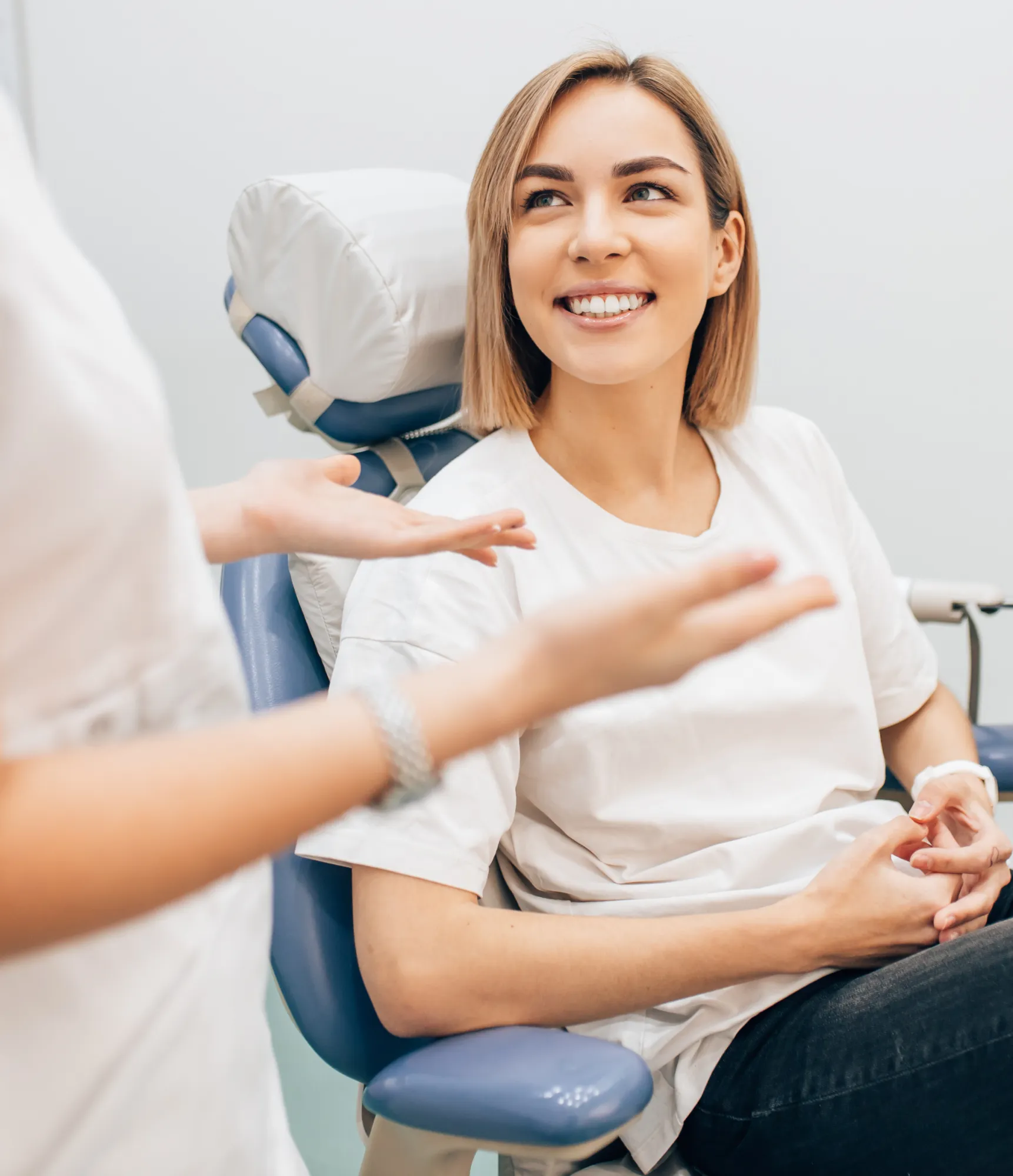 A dental hygienist cleans a young boy's teeth while another child watches closely.