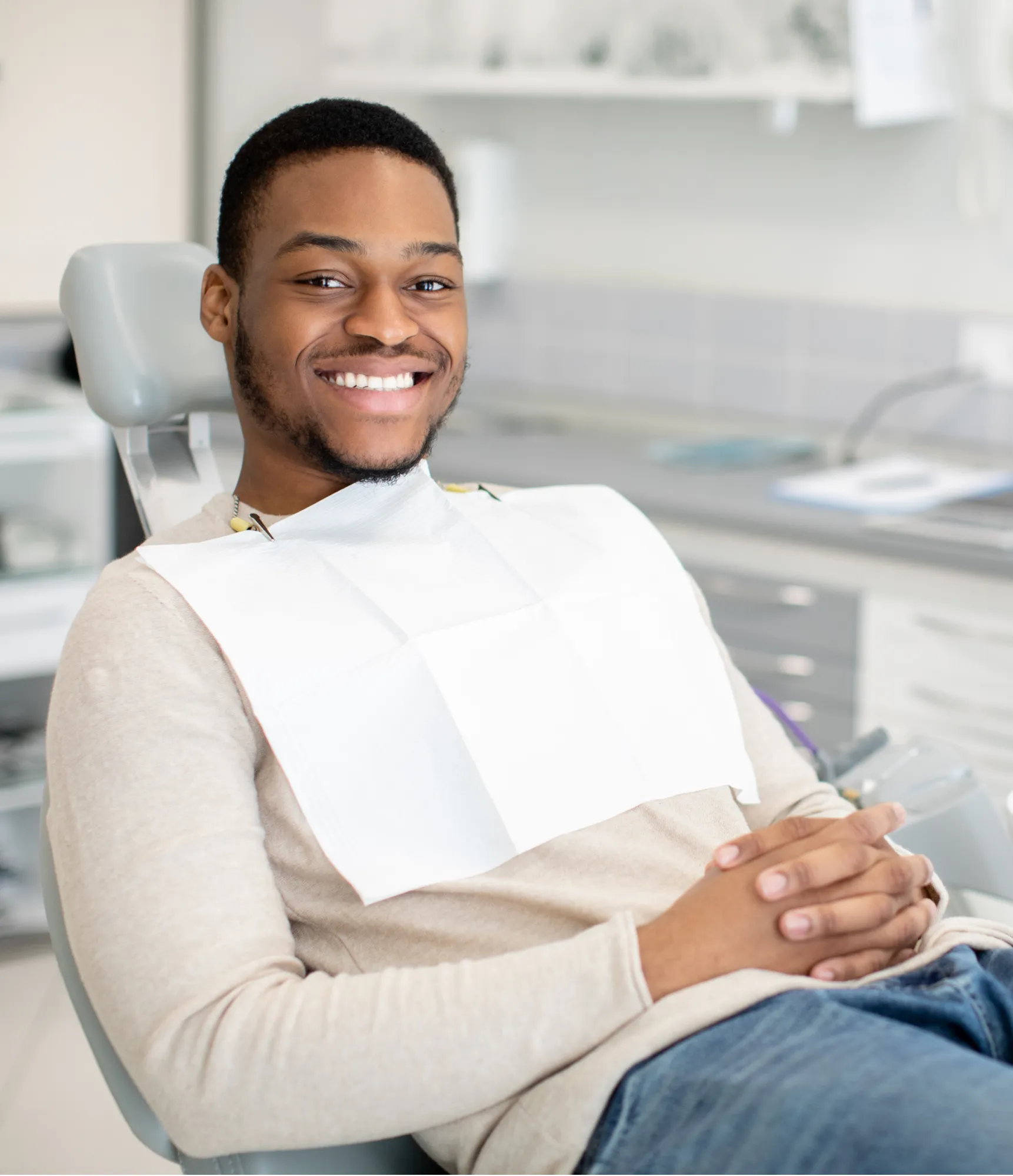A person wearing a striped shirt smiles while resting their chin on their hand.