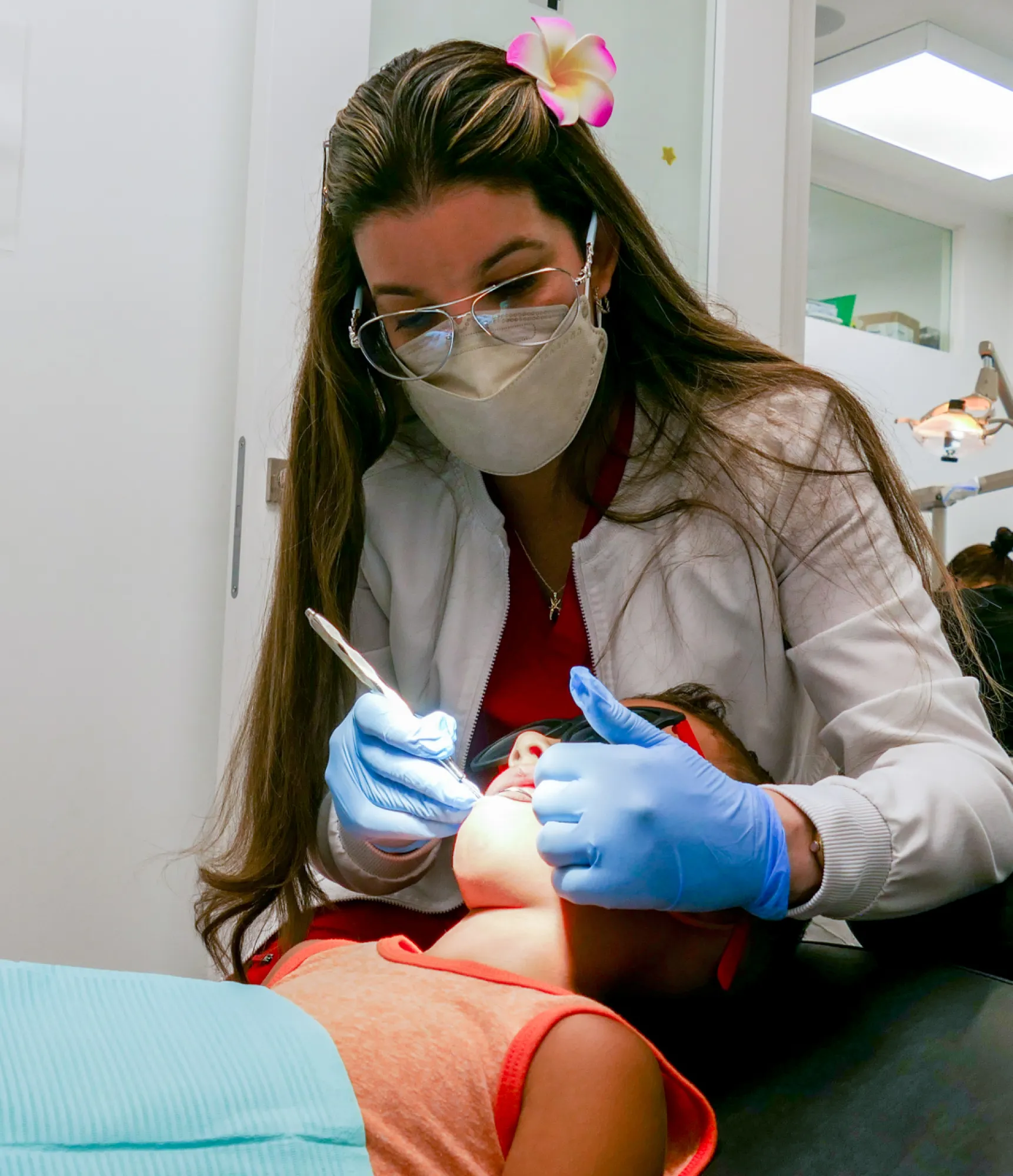 Smiling woman in black scrubs answering a phone call at a reception desk with computers.