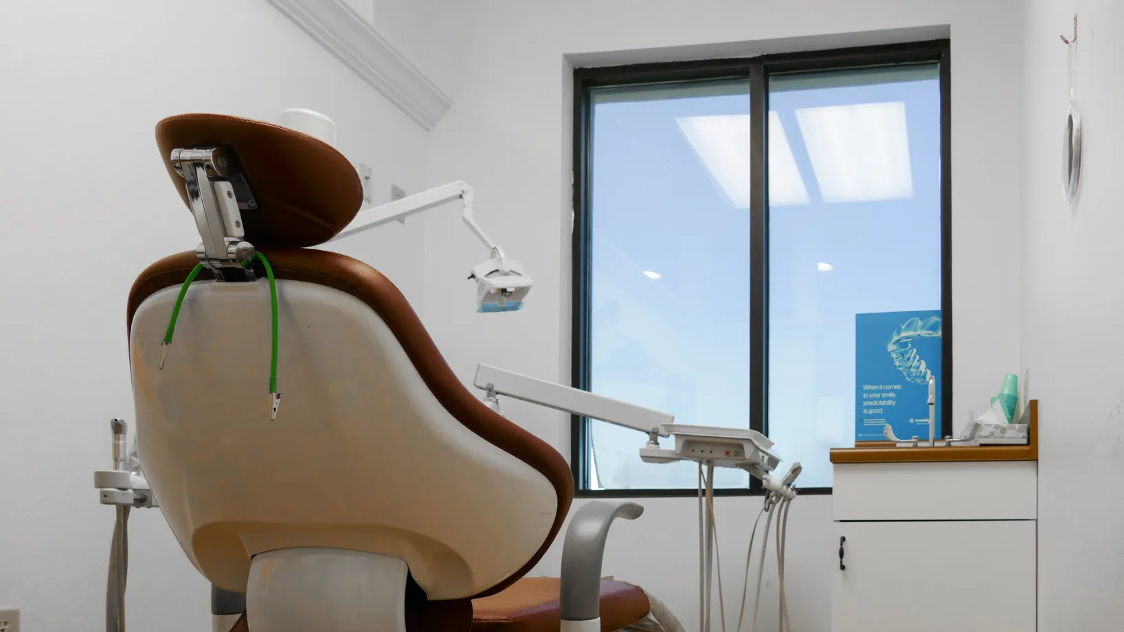A dental chair and equipment are set up in a clean, modern dentist's office.