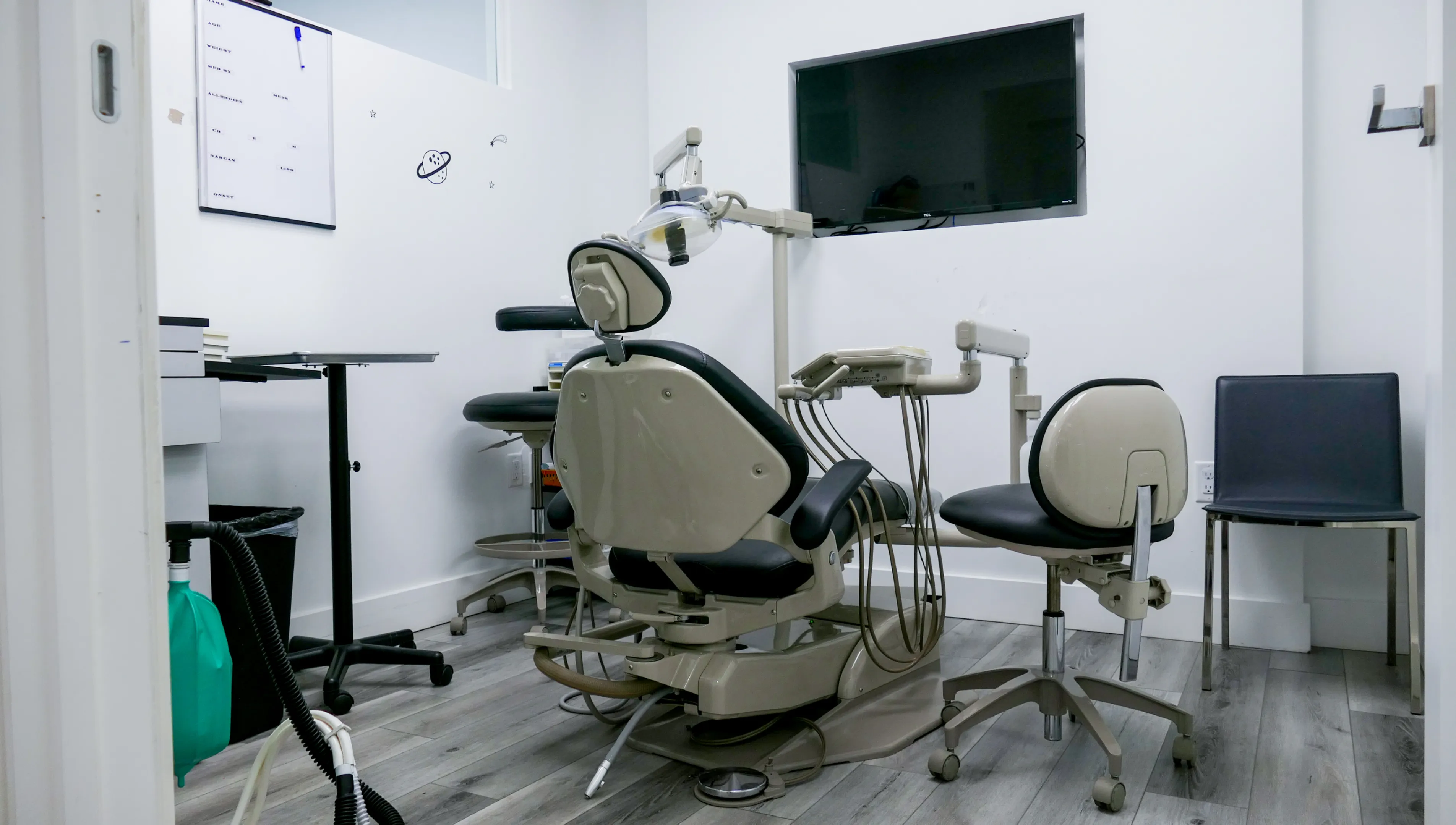 A dental office hallway with an X-ray machine and patient chair visible in the background.