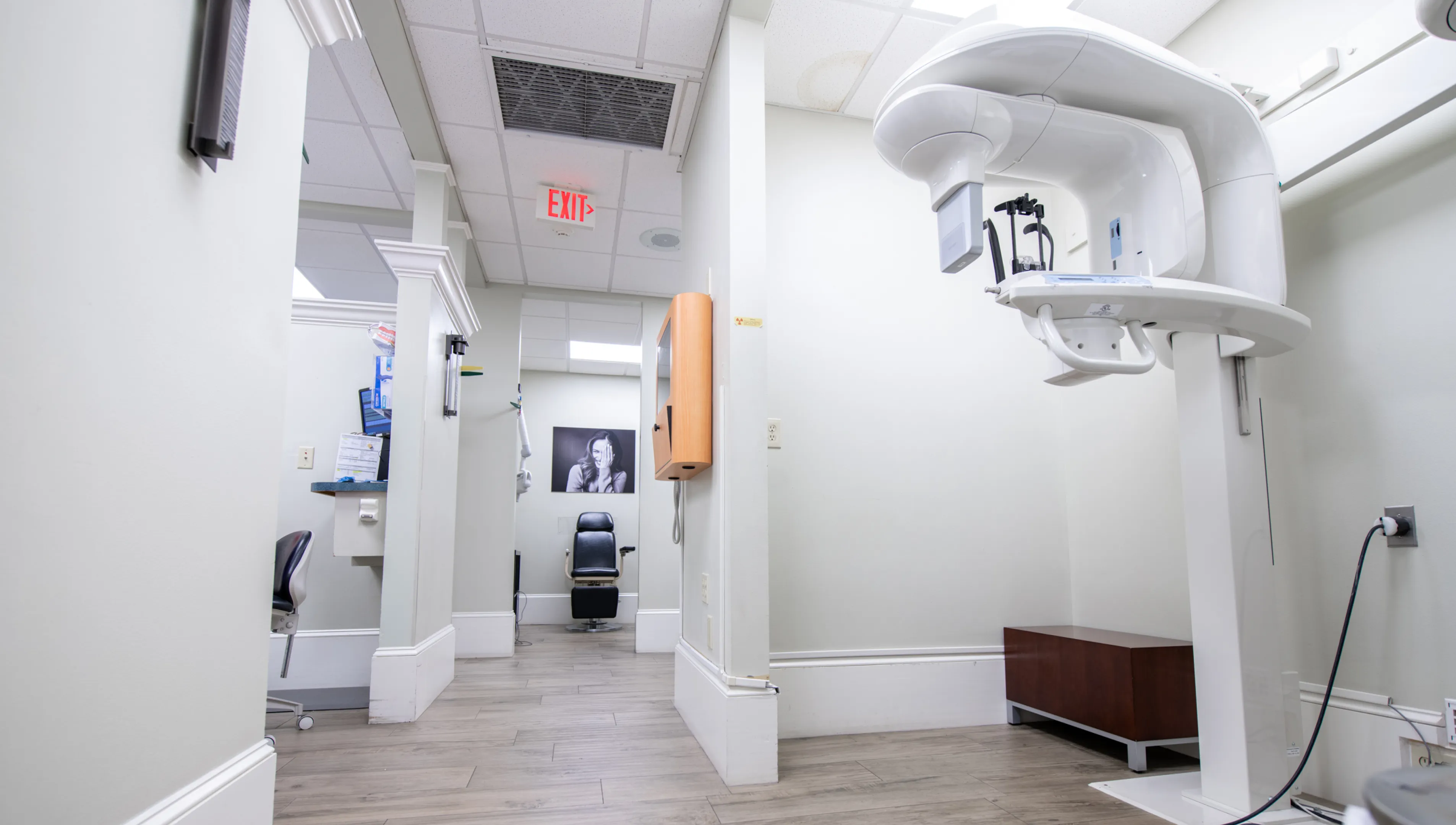 A waiting room with three chairs, a couch, and a wooden table with a plant.