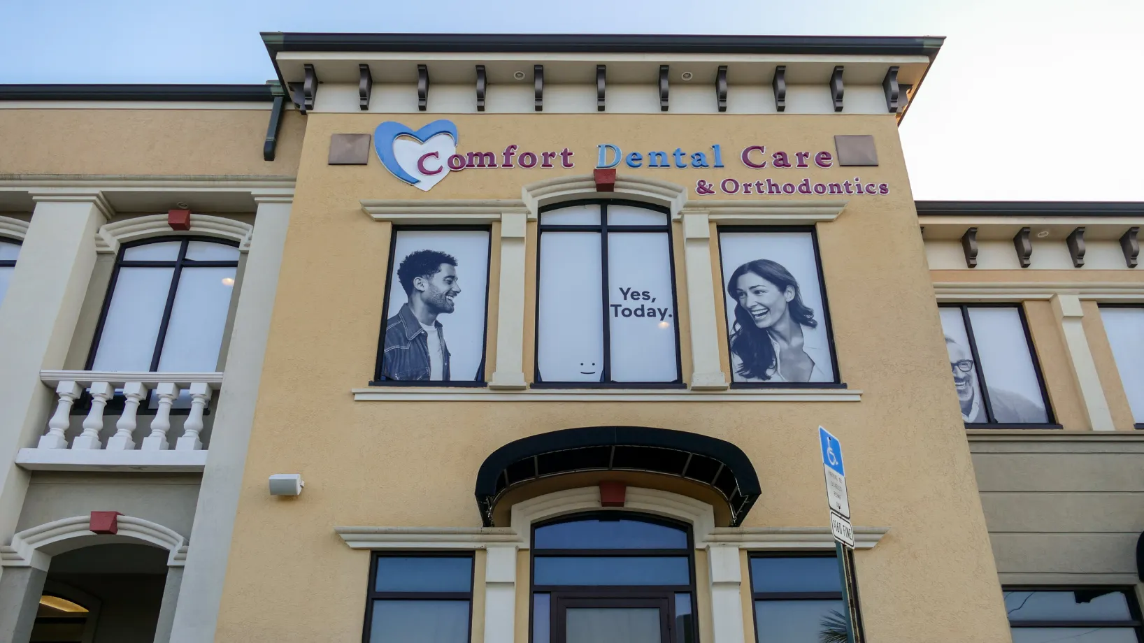 A dental office building with large photos of smiling people on the upper windows.