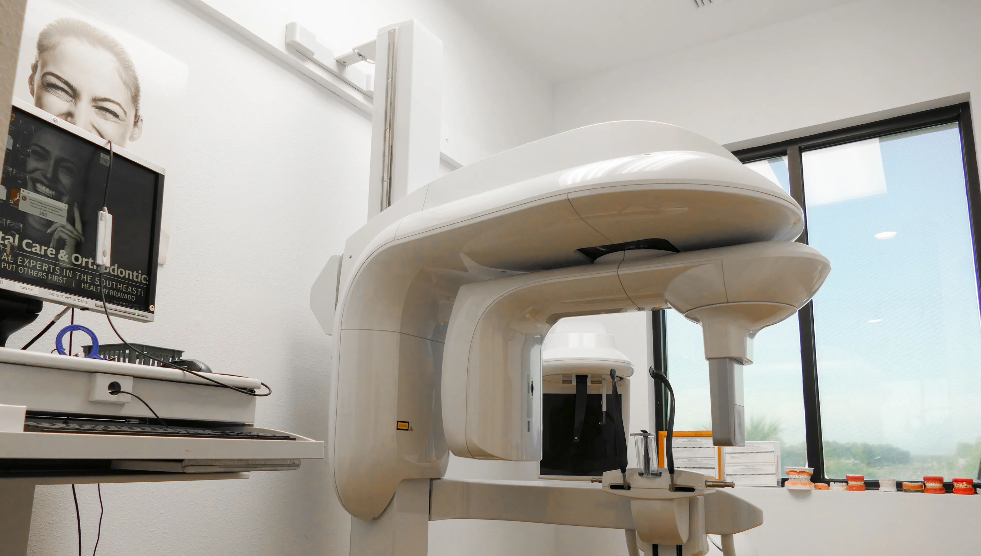 A group of nine dental care professionals, smiling and pointing, pose together in an office.