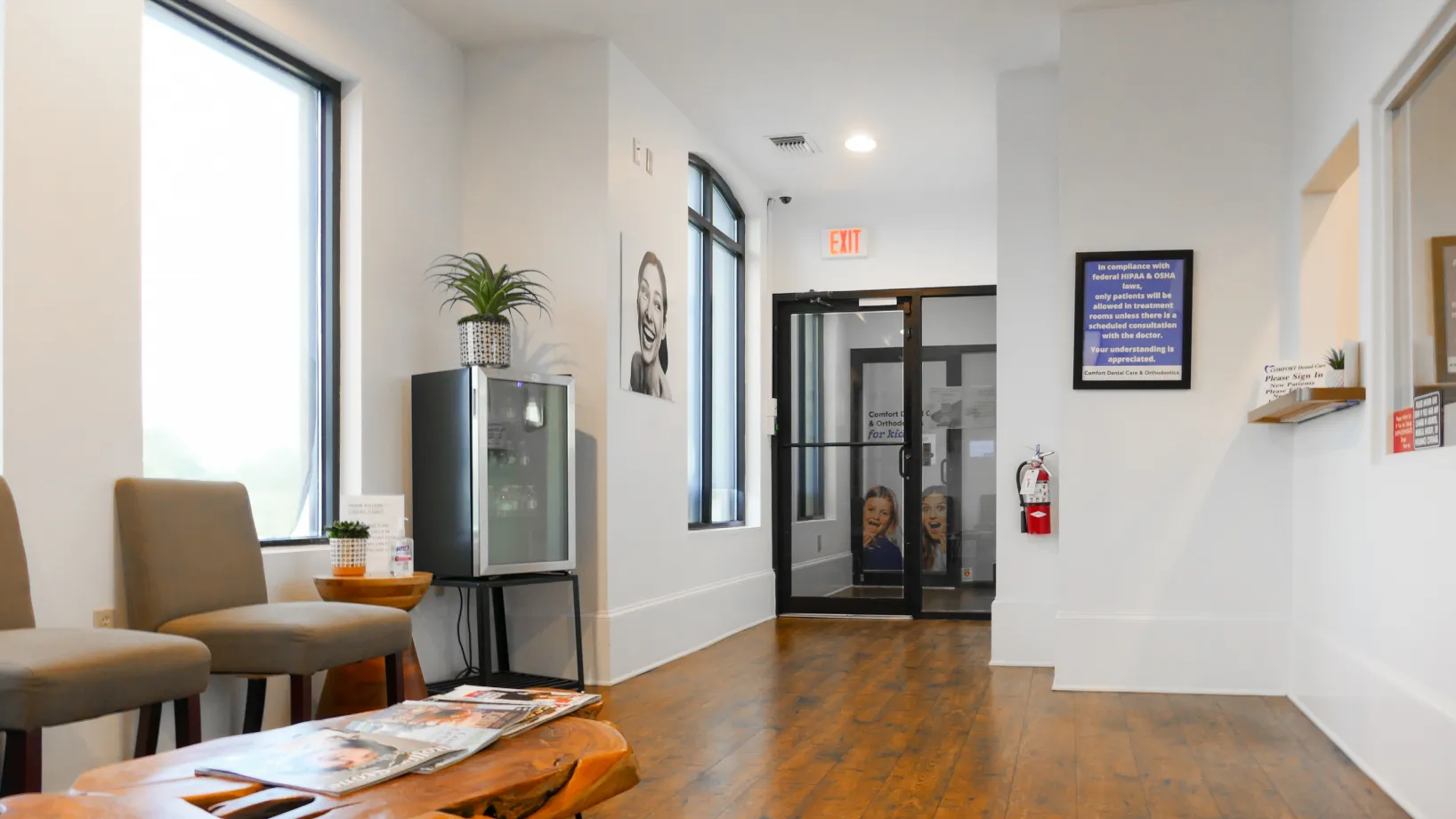 A waiting room with chairs, a water cooler, and a glass door leading to another area.