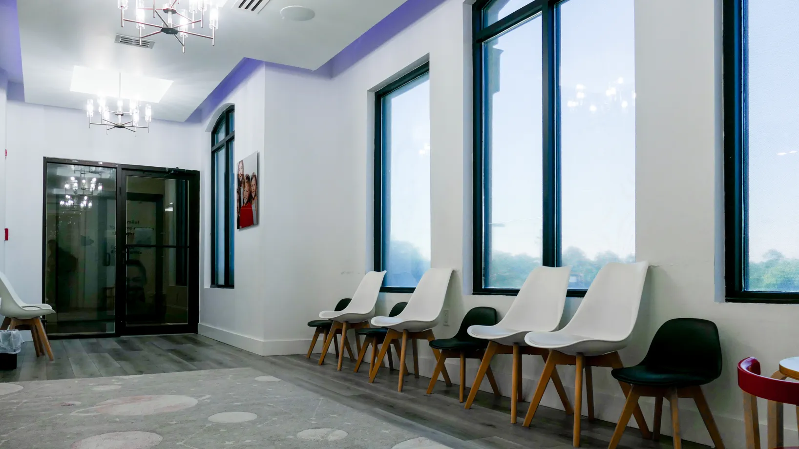 Small round table with colorful chairs and toys, next to a window in a children's room.