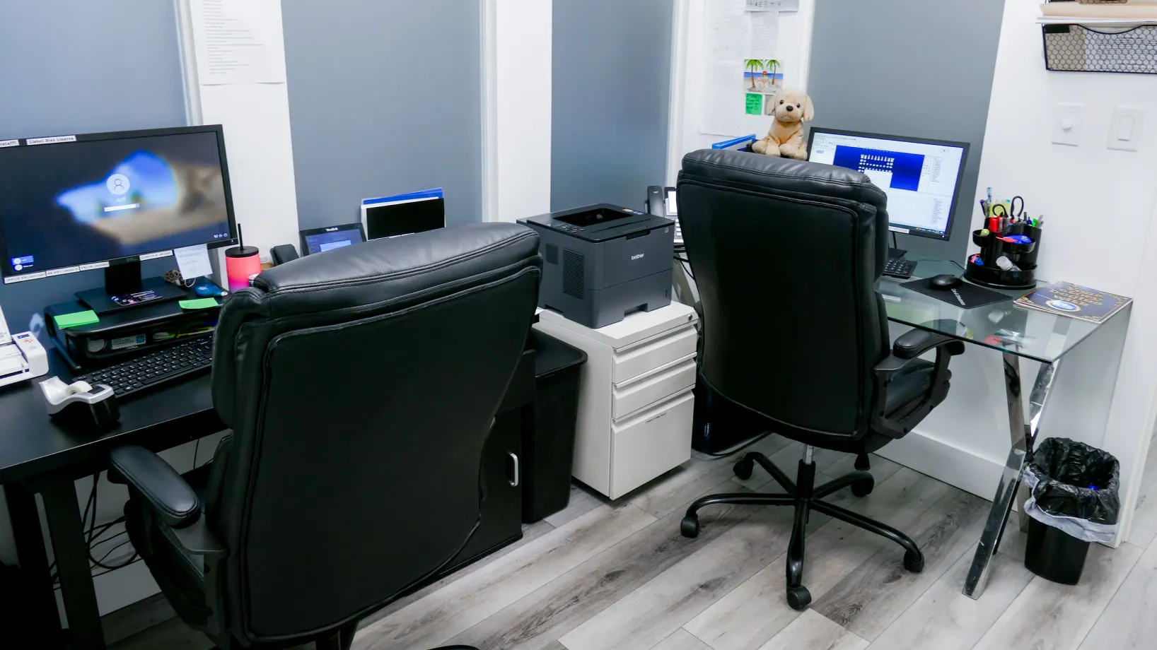 Two office desks with computers and chairs in a small workspace.