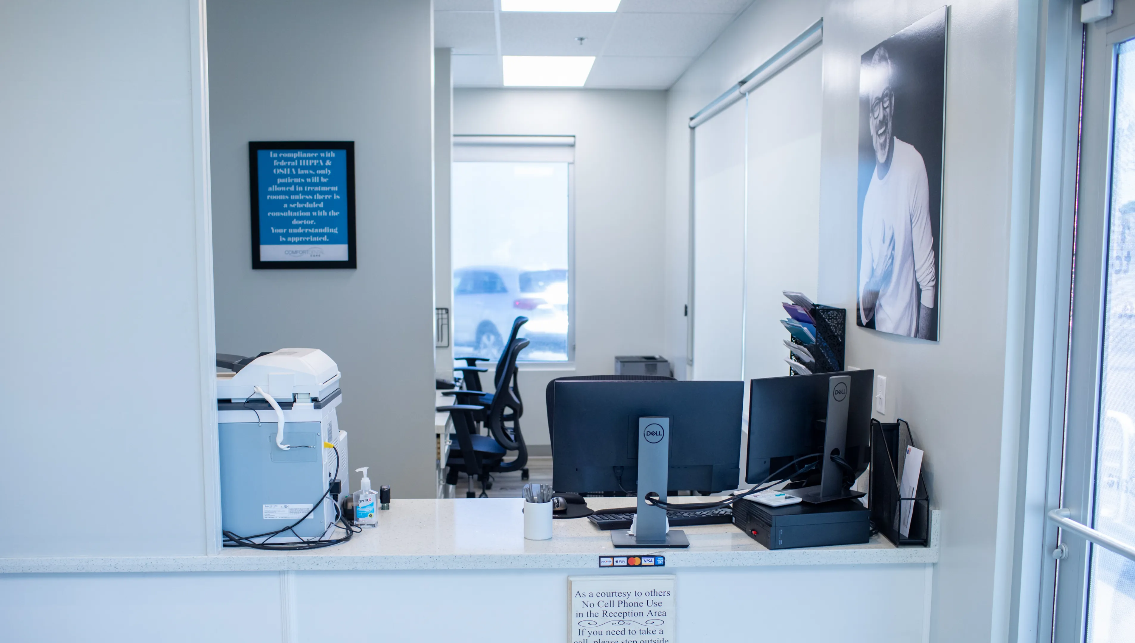 A woman in scrubs and blue gloves holds safety glasses, standing in a brightly lit room.