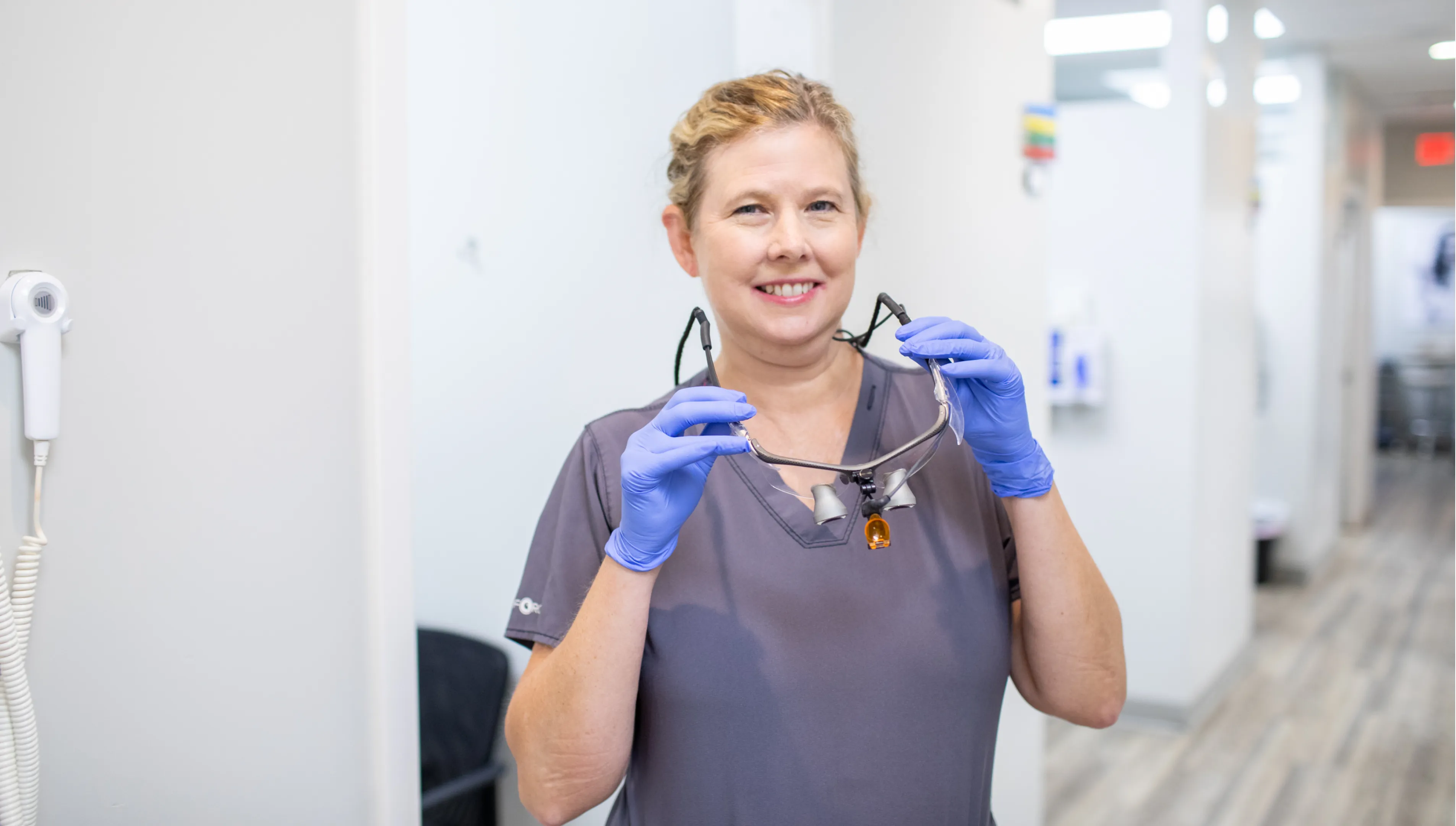 Two women in an office setting talk while working at a computer desk.