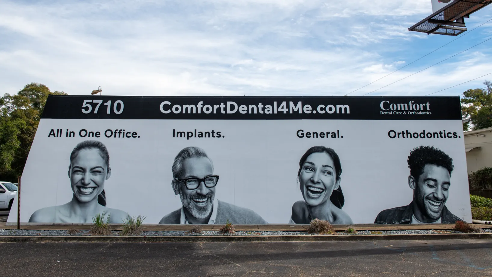A billboard advertising dental services with photos of four smiling people.