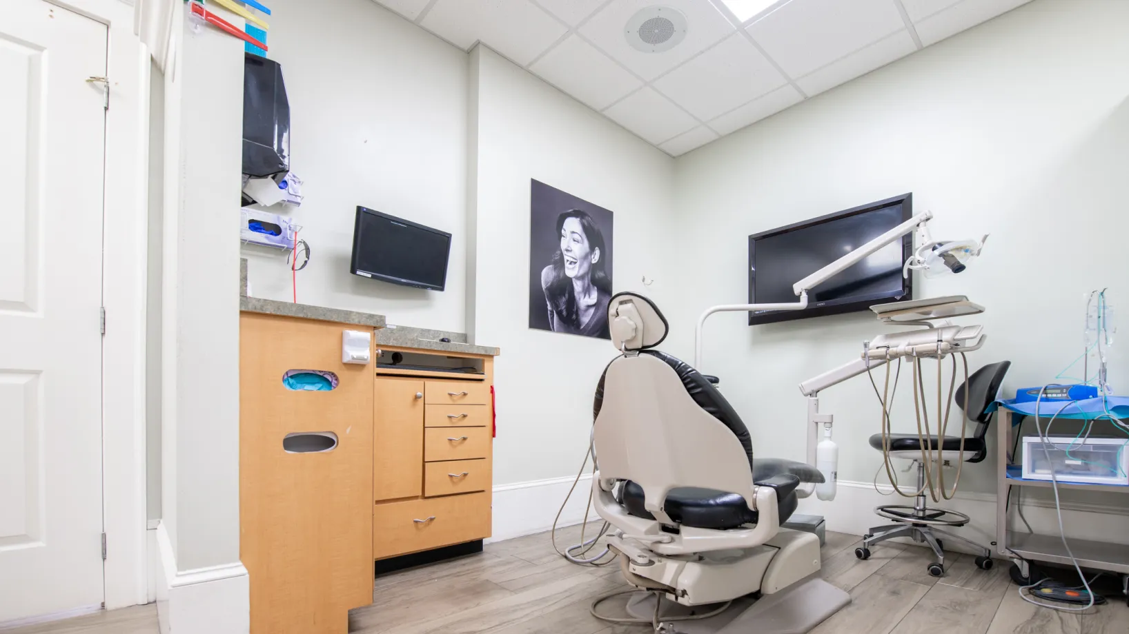 A dental professional examines a patient in a dental office, using specialized equipment.
