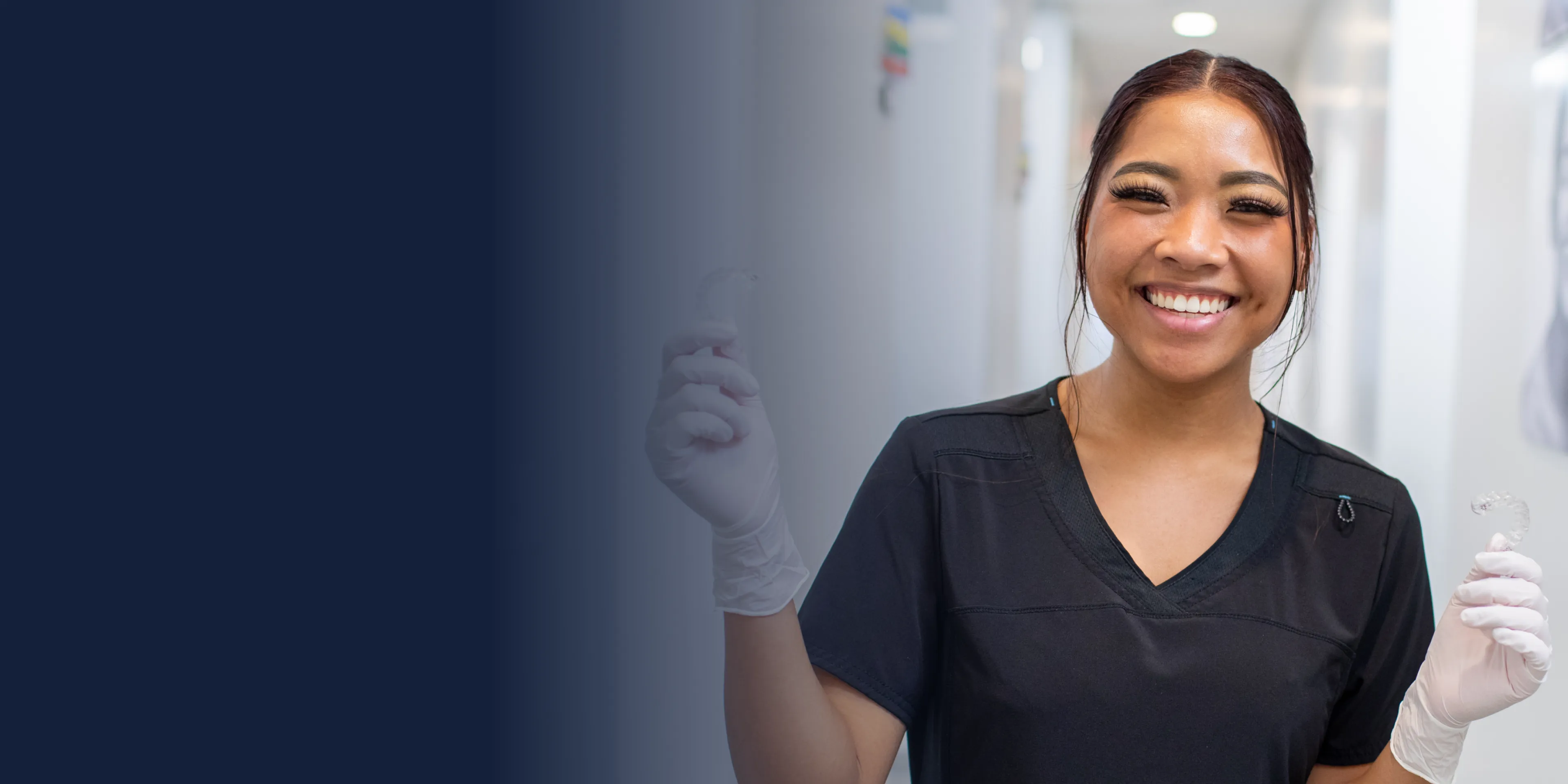 Person smiling and looking to the side, wearing a dark top.