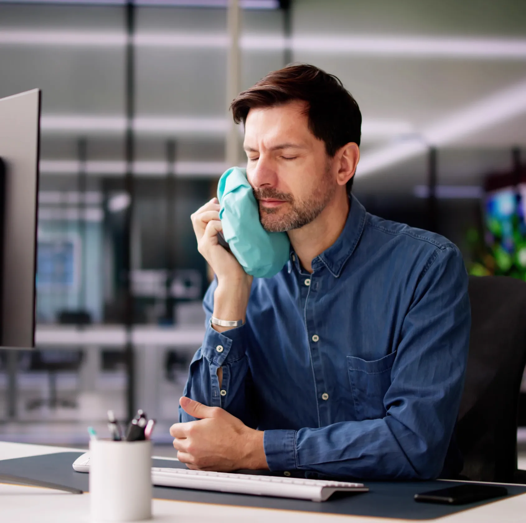 Two dental professionals, a man and a woman, stand smiling with arms crossed in a dentist's office.