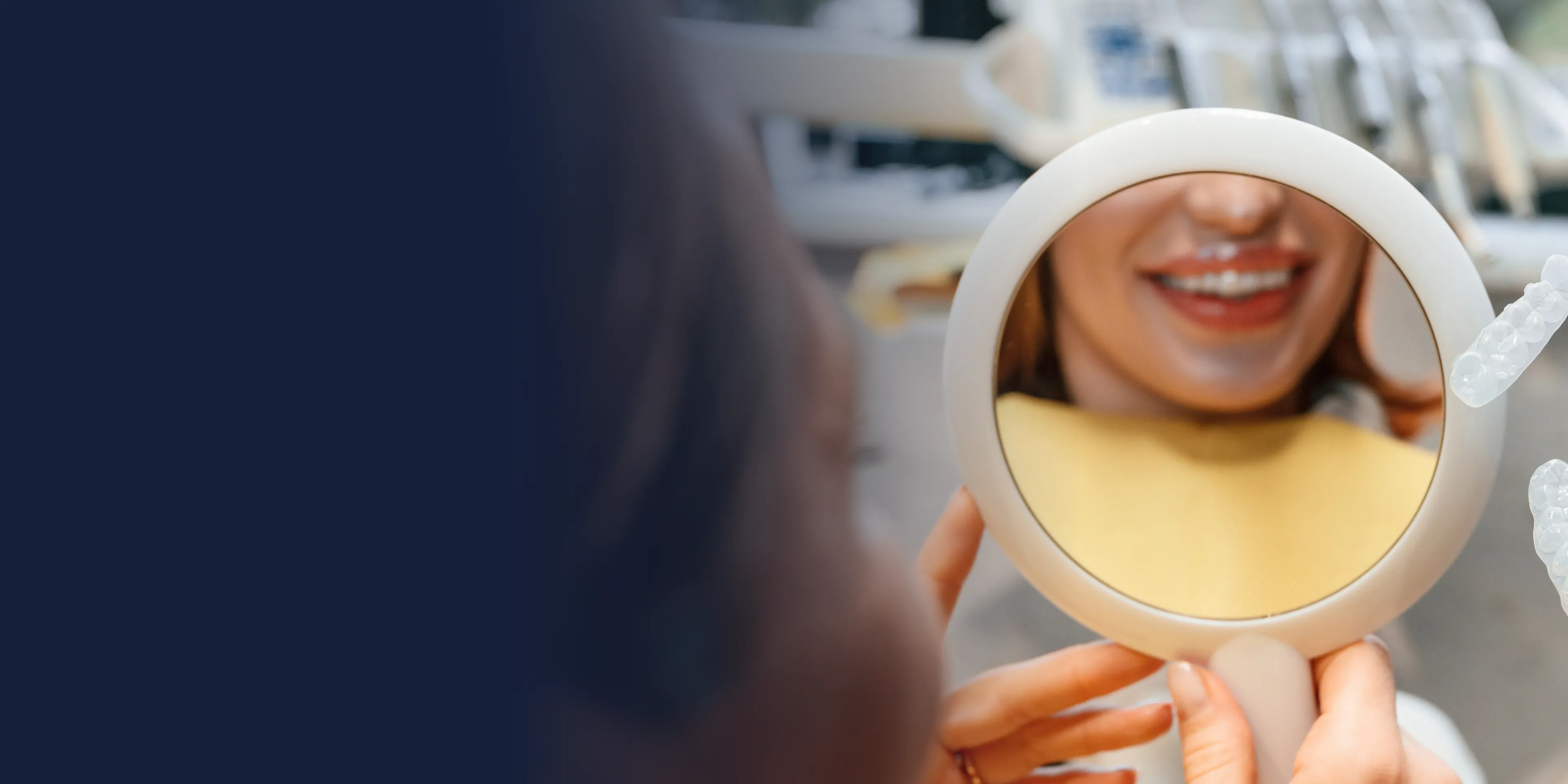 A person holds a round mirror, reflecting their smiling face.