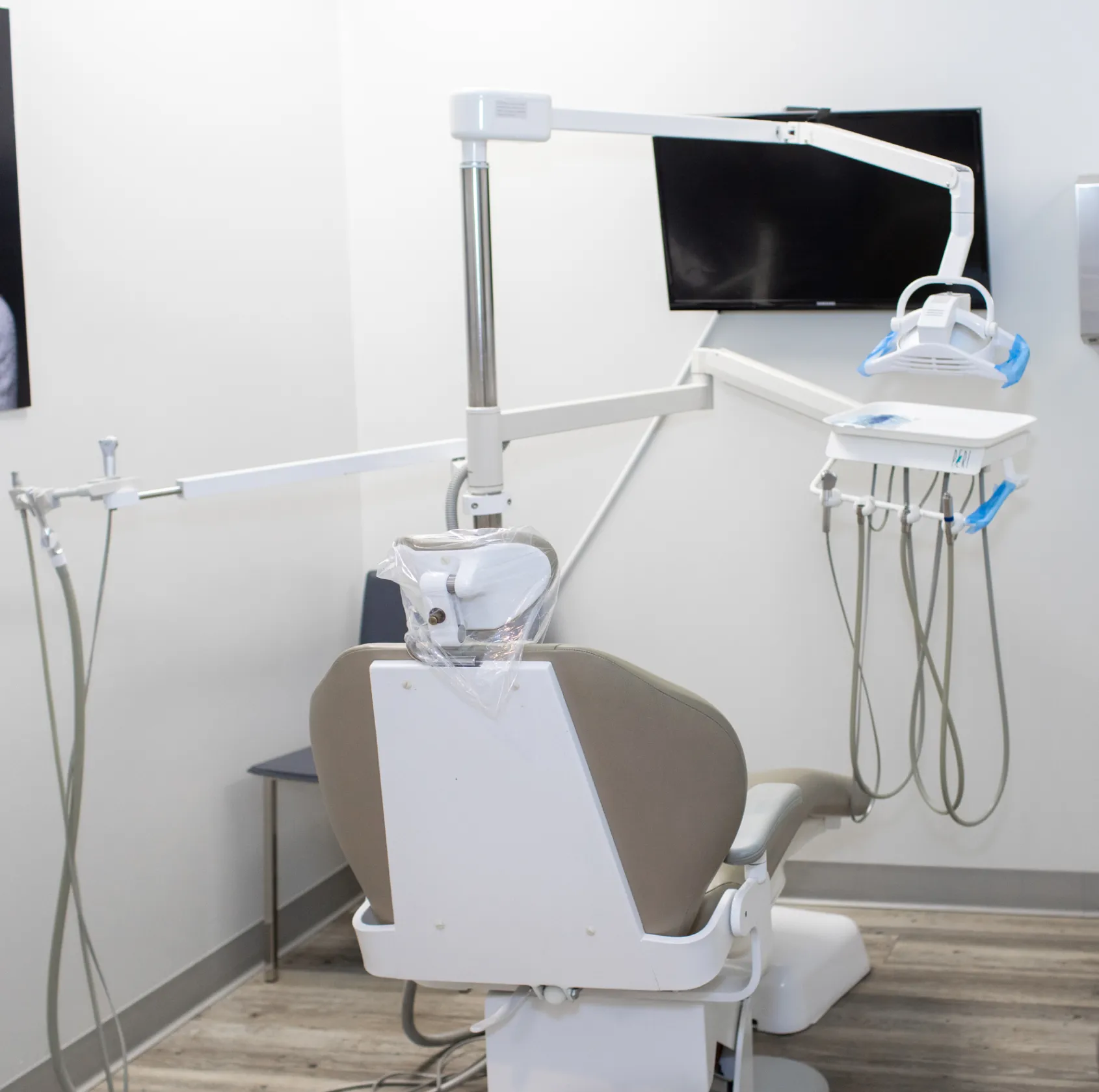 A dentist's chair with overhead light and dental equipment in a clean, modern clinic room.