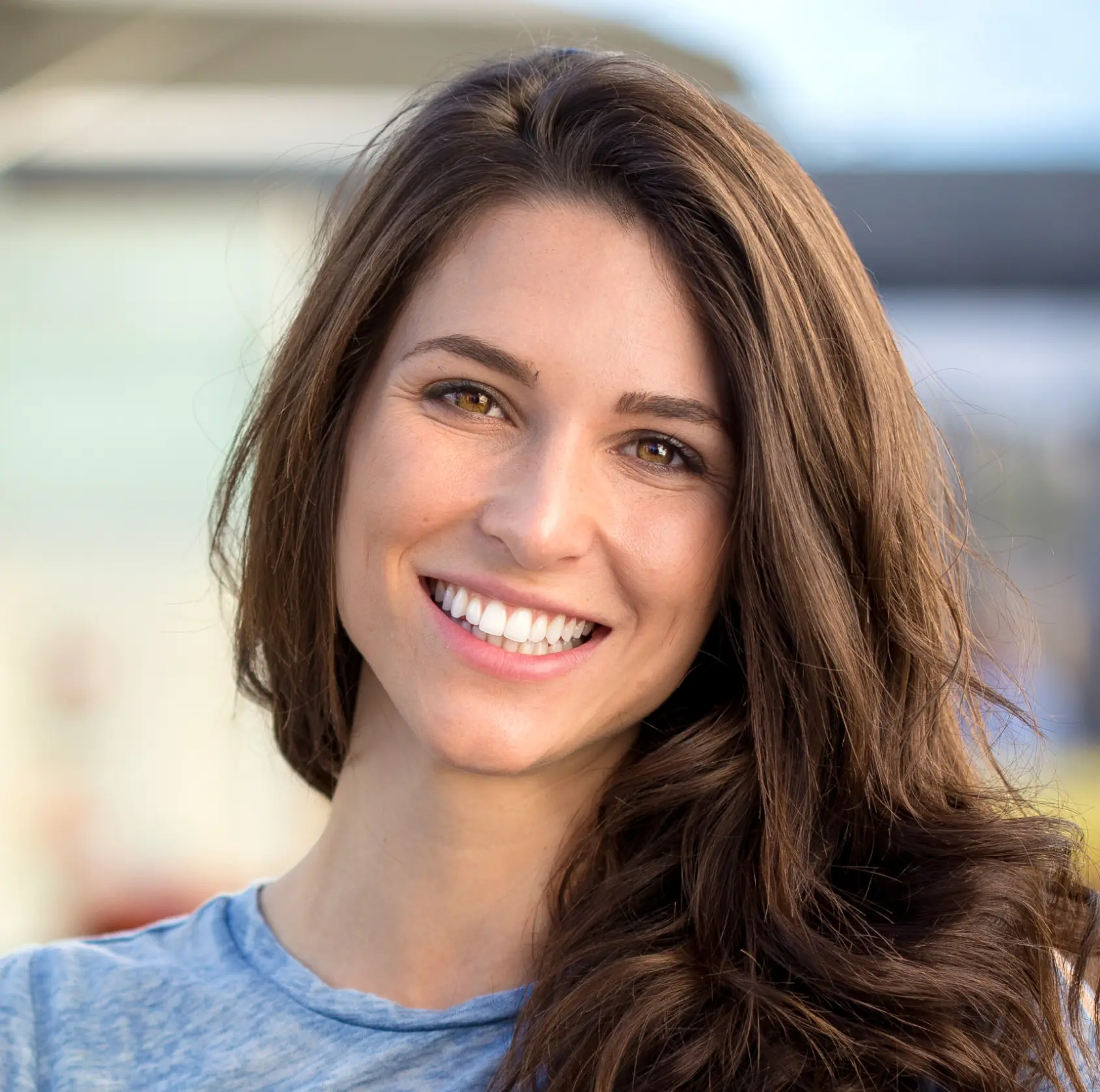A woman with long hair is smiling directly at the camera.