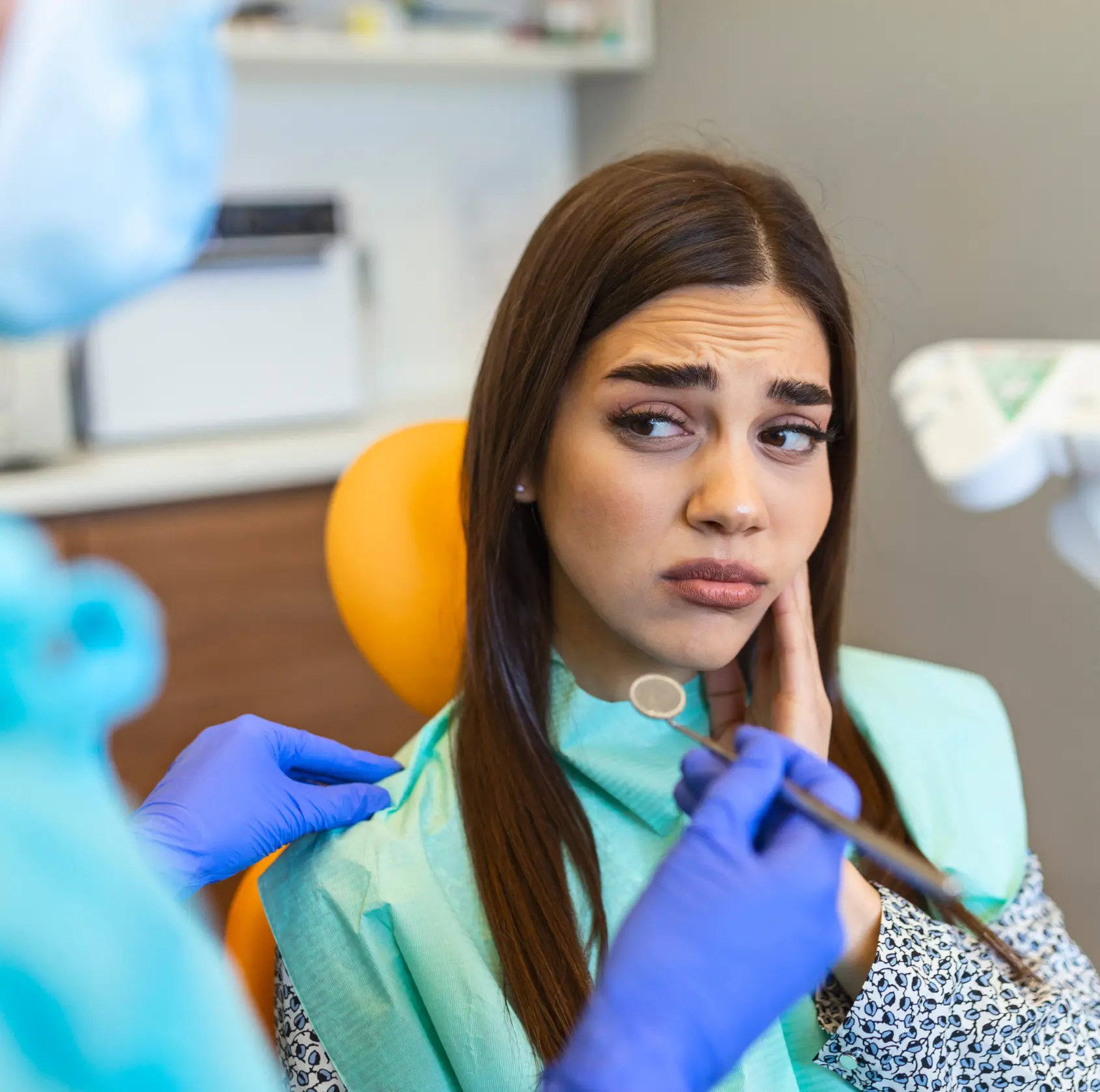 A woman looks concerned while sitting in a dentist's chair during a dental check-up.