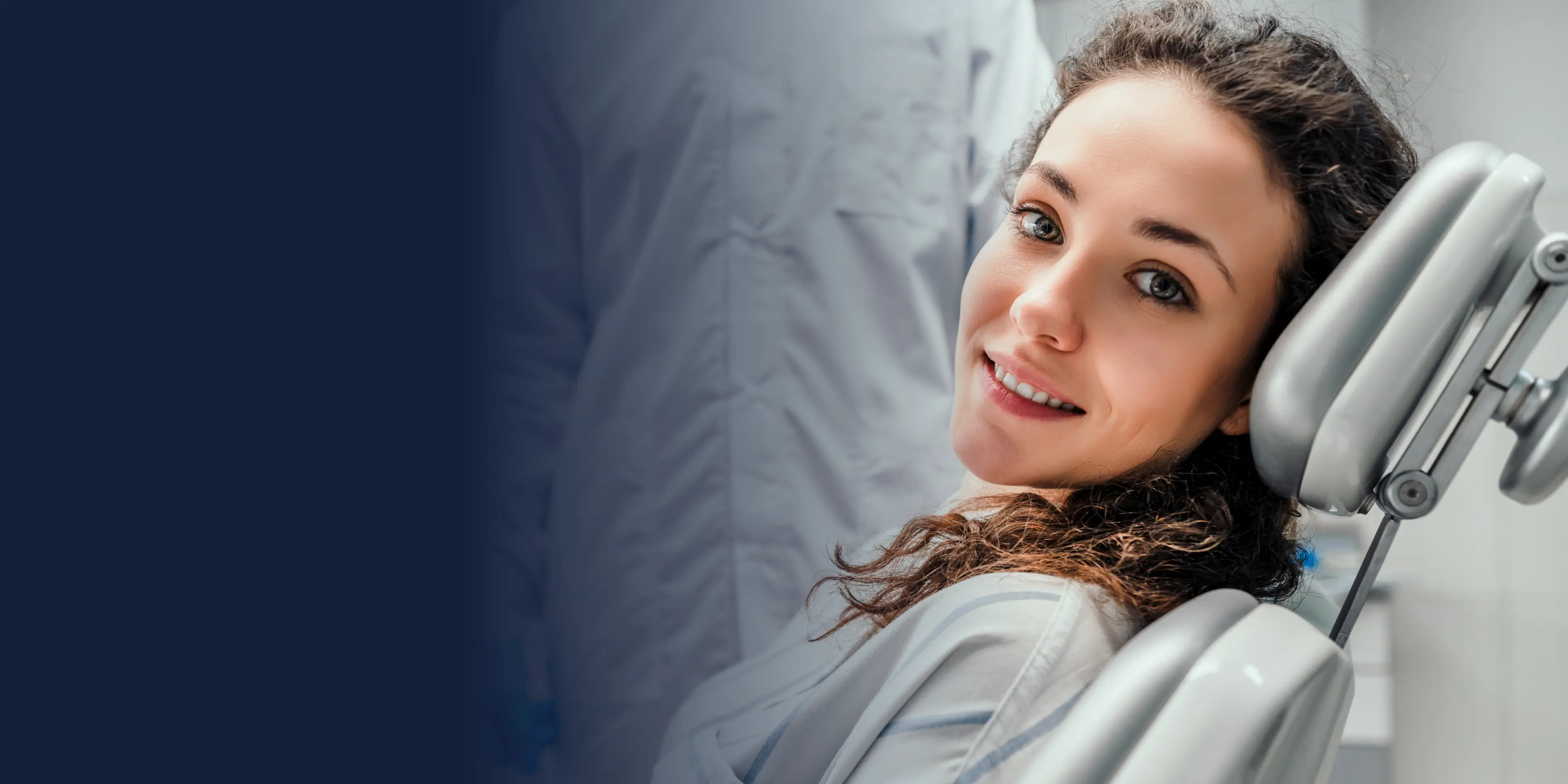 Woman sitting in a dental chair, smiling at the camera.