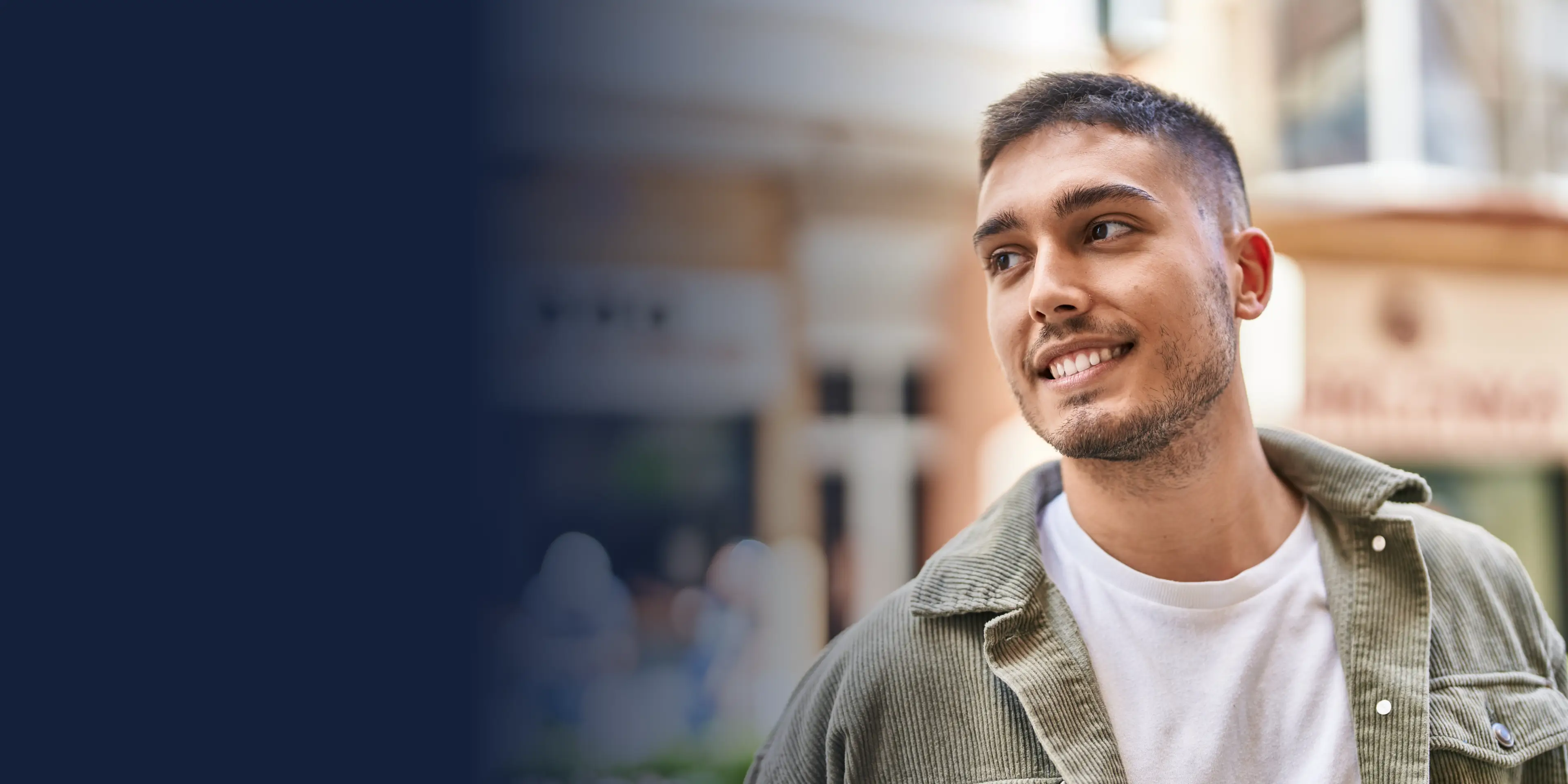 A person in a green jacket smiles while standing outside in a casual setting.