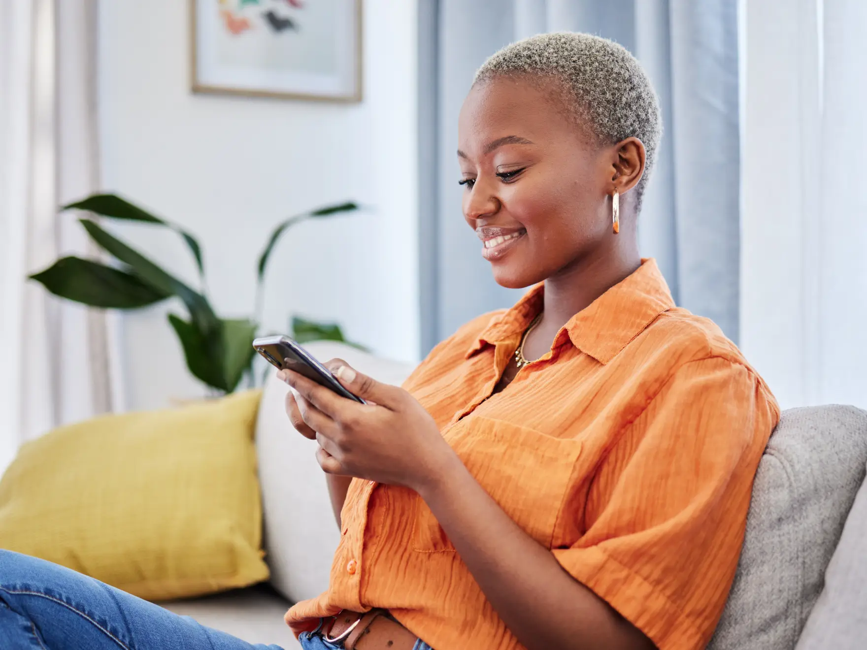 Person in an orange shirt smiling while looking at their phone.