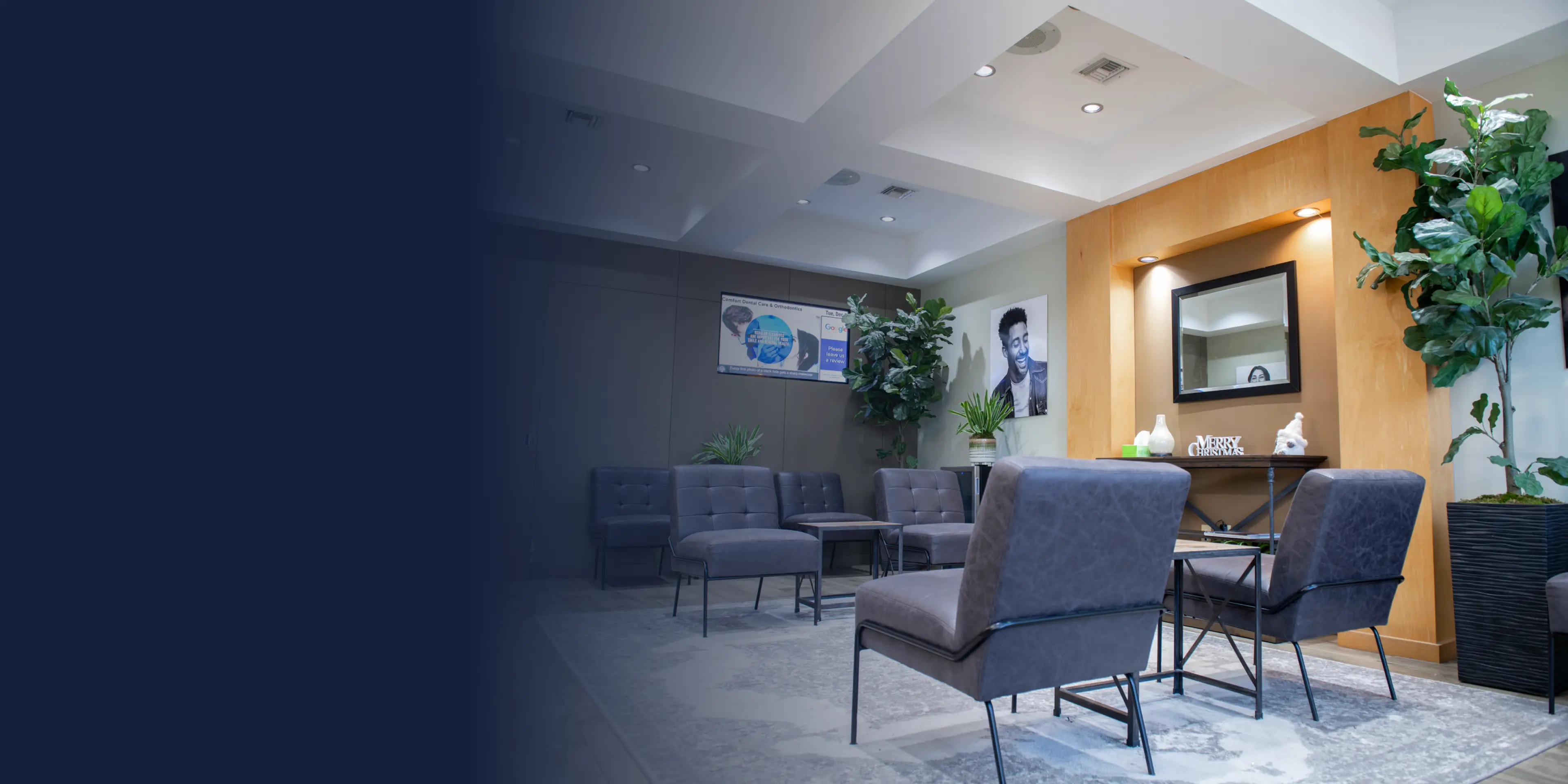 A waiting room with gray chairs, a wooden accent wall, and a large mirror above a table.
