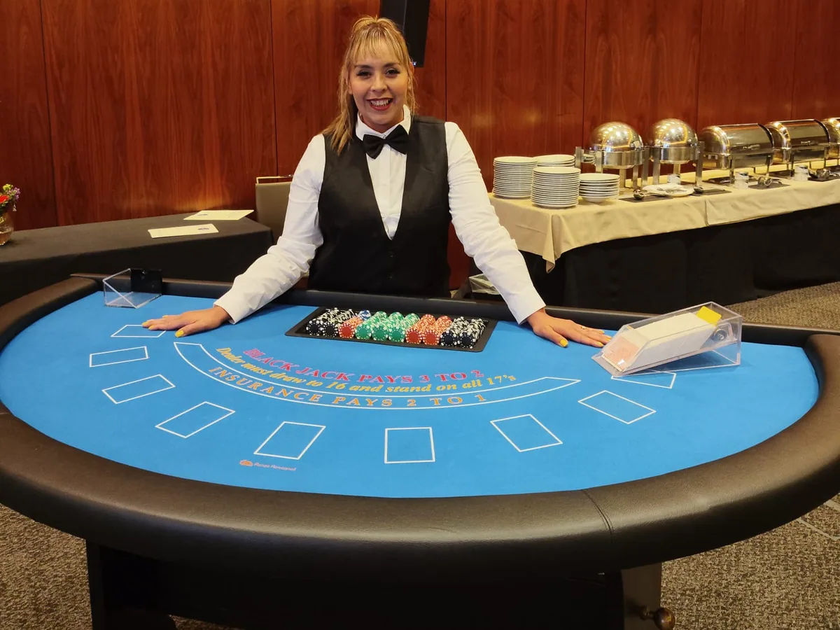 Mesa real de blackjack, con crupier, fichas y las marcas originales del tapete azul.