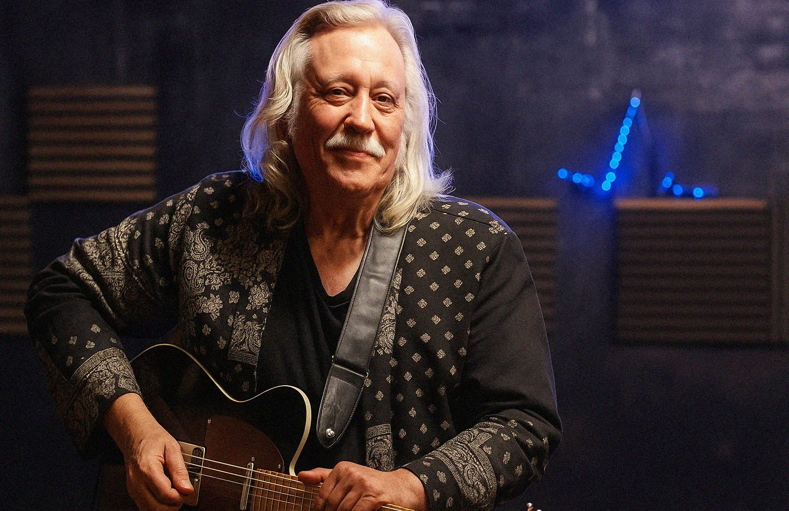 Retrato de guitarrista con guitarra semiacústica en un escenario con luz azul