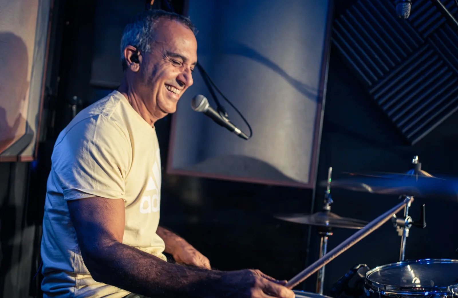 Baterista sonriendo tras los platos en un concierto de sala