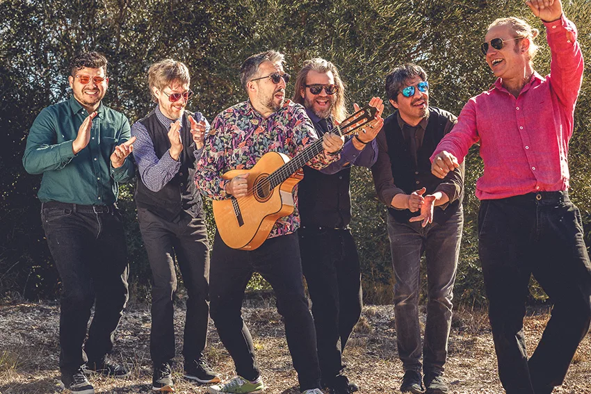 Los seis músicos de la banda tocando palmas al aire libre entre olivos