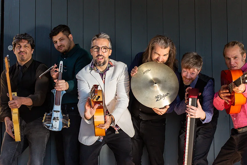 La banda posando con sus instrumentos: guitarras, violín, teclado y plato
