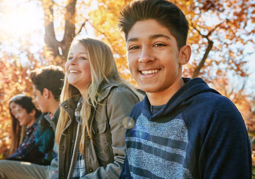 Group of teens happily sitting outside together
