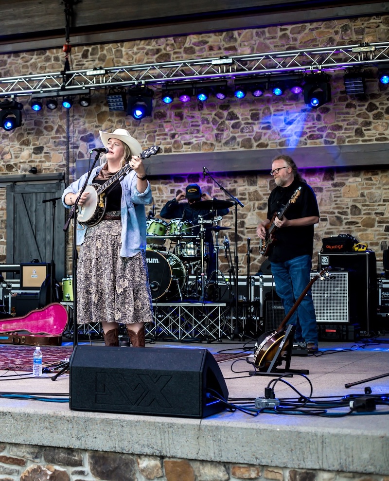 Woman playing a banjo on a stage with band in the background