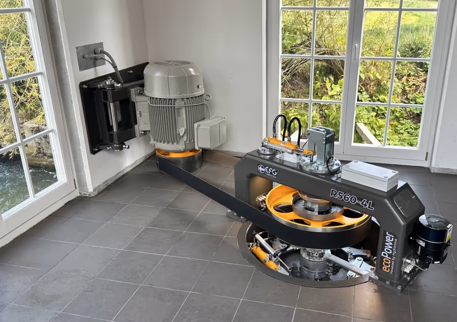 EcoPower R560-4L micro-hydropower turbine installed indoors on a tiled floor near windows.