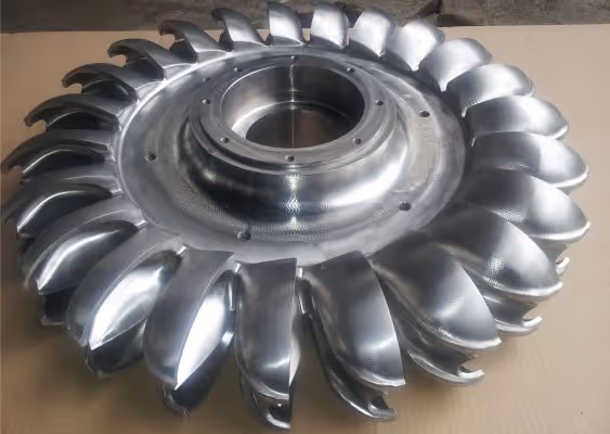 Polished metal turbine impeller with curved blades arranged in a circular pattern.