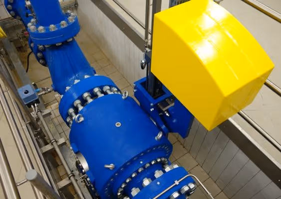 Large industrial blue pipeline connected with numerous bolts and a mounted yellow machinery component.