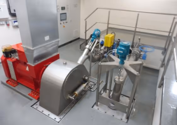 Industrial machinery setup with a red base unit connected to silver and blue components and tubing in a clean, enclosed workspace.