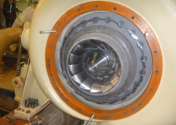 Close-up of a metallic turbine or compressor component inside a circular housing with orange rim.