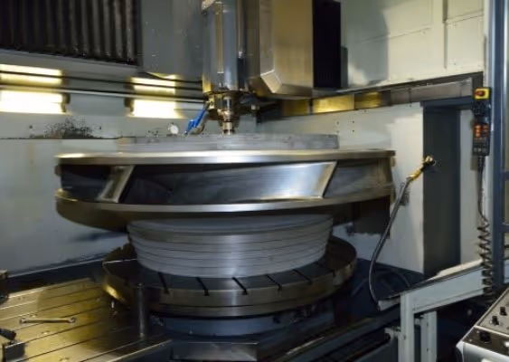 Industrial CNC machine milling a large circular metal component inside a manufacturing facility.