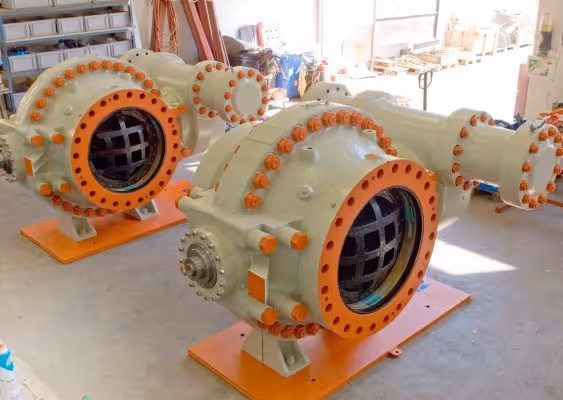 Two large industrial machines with orange and beige coloring placed on an indoor concrete floor.