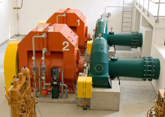 Industrial machinery with two large orange units labeled 1 and 2 connected to green pipes inside a clean mechanical room.