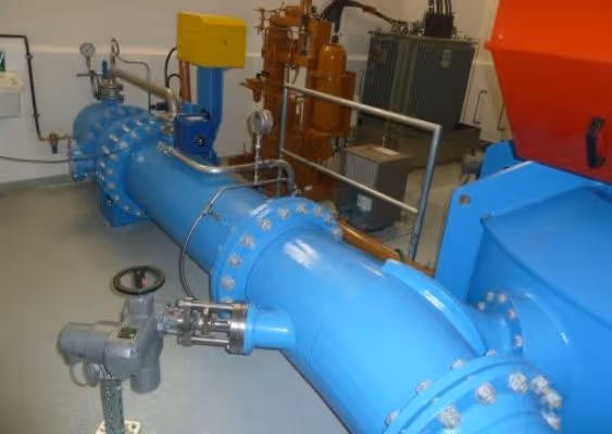 Large blue industrial pipeline with valves and gauges inside a facility.